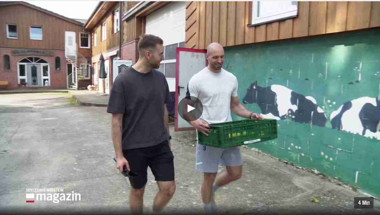 Marco und Maik Möller bringen Äpfel zu Kuh Mausi. Sie sprechen miteinander. Unten links sieht man das Logo vom Schleswig-Holstein-Magazin.