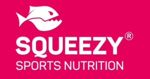 Logo von Squeezy Sports Nutrition, das einen stilisierten Fisch mit geöffnetem Maul und den Schriftzug „SQUEEZY SPORTS NUTRITION“ in weißen Buchstaben auf einem leuchtend pinken Hintergrund zeigt.
