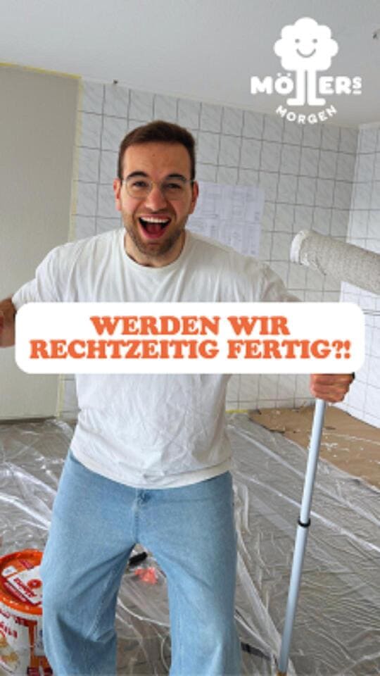 Das Bild zeigt eine Person, die in einem Raum steht, der gerade renoviert wird. Die Person trägt ein weißes T-Shirt und eine Jeans und hält eine Farbrolle in der rechten Hand. Der Boden ist mit Plastikfolie abgedeckt, und es gibt einen Eimer mit Farbe oder Spachtelmasse in der Nähe. Die Wände sind teilweise mit Fliesen bedeckt, und es scheint, als ob weitere Renovierungsarbeiten im Gange sind. Über dem Bild ist ein Text mit der Aufschrift "Werden wir rechtzeitig fertig?!" zu sehen, was darauf hindeutet, dass die Person möglicherweise unter Zeitdruck steht, um die Renovierungsarbeiten abzuschließen. Das Logo "Möllers Morgen" ist in der oberen rechten Ecke des Bildes sichtbar, was darauf hinweist, dass die Person möglicherweise mit diesem Betrieb verbunden ist.