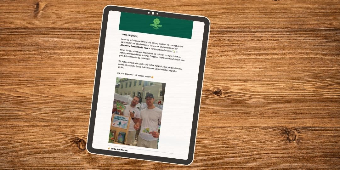 Das Bild zeigt ein Tablet, das auf einem Holztisch liegt. Auf dem Bildschirm des Tablets ist eine Webseite zu sehen, die Informationen über einen Bauernhof präsentiert. Die Webseite enthält ein Bild von zwei Personen, die auf einem Feld stehen und lächeln. Der Text auf der Webseite ist nicht vollständig lesbar, aber es scheint sich um eine Beschreibung des Bauernhofs und seiner Aktivitäten zu handeln. Der Text erwähnt unter anderem den Anbau von Gemüse und die Haltung von Tieren. Die Webseite hat ein grünes Design mit einem Logo oben links, das möglicherweise das Logo des Bauernhofs ist.