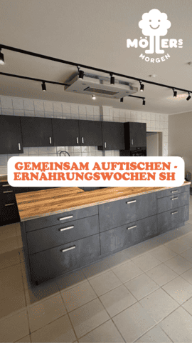Eine moderne Küche mit dunkelgrauen Schränken und einer großen Insel in der Mitte, die eine Arbeitsplatte aus Holz hat. Über der Insel hängen Spotlights, und die Wände sind mit hellen Fliesen verkleidet. Im Vordergrund steht in großen, orangefarbenen Buchstaben: GEMEINSAM AUFTISCHEN – ERNÄHRUNGSWOCHEN SH. Das Logo von Möllers Morgen ist in der oberen rechten Ecke sichtbar. Die Küche wirkt einladend und funktional.