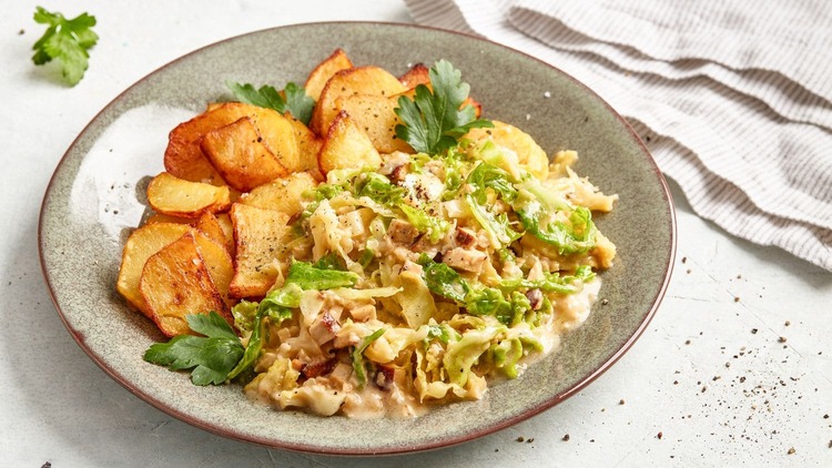 Ein herzhafter Teller mit **Bratkartoffeln und Rahmwirsing**. Die Kartoffeln sind goldbraun und knusprig gebraten, während der Rahmwirsing in einer cremigen Sauce mit frischen Petersilienblättern garniert ist. Das Gericht wirkt deftig, lecker und perfekt für eine gemütliche Mahlzeit! Ein Genuss für alle, die traditionelle Küche lieben.