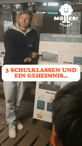 Das Bild zeigt einen jungen Mann, der vor einer Gruppe von Schüler:innen steht und eine Präsentation hält. Im Hintergrund ist ein Plakat mit dem Titel **"Der Hof Möller"** zu sehen. Im Vordergrund steht in großen, orangefarbenen Buchstaben: **"3 SCHULKLASSEN UND EIN GEHEIMNIS..."** Das Logo von **Möllers Morgen** ist in der oberen rechten Ecke sichtbar. Die Szene wirkt wie eine interaktive Führung oder ein Bildungsprojekt, bei dem Schulklassen den Hof und die Arbeit von Möllers Morgen kennenlernen. Der Mann scheint engagiert zu erklären, was das Geheimnis sein könnte.