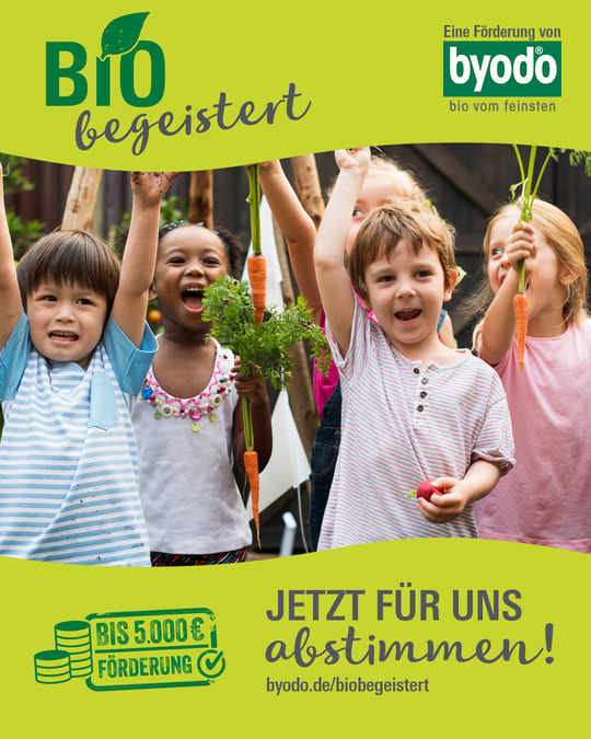 Das Bild zeigt eine fröhliche Gruppe von Kindern, die stolz frisches Gemüse wie Karotten in die Höhe halten. Im Hintergrund ist ein grüner Banner mit dem Aufdruck:
**"BIO begeistert"**
und
**"Eine Förderung von byodo – bio vom feinsten"**
Darunter steht ein Aufruf zum Mitmachen:
**"JETZT FÜR UNS ABSTIMMEN!"**
sowie der Hinweis:
**"BIS 5.000 € FÖRDERUNG"**
Die Kinder wirken begeistert und engagiert, was die Freude an Bio-Lebensmitteln und nachhaltiger Landwirtschaft unterstreicht. Der Link **byodo.de/biobegeistert** lädt dazu ein, für das Projekt abzustimmen und es zu unterstützen.