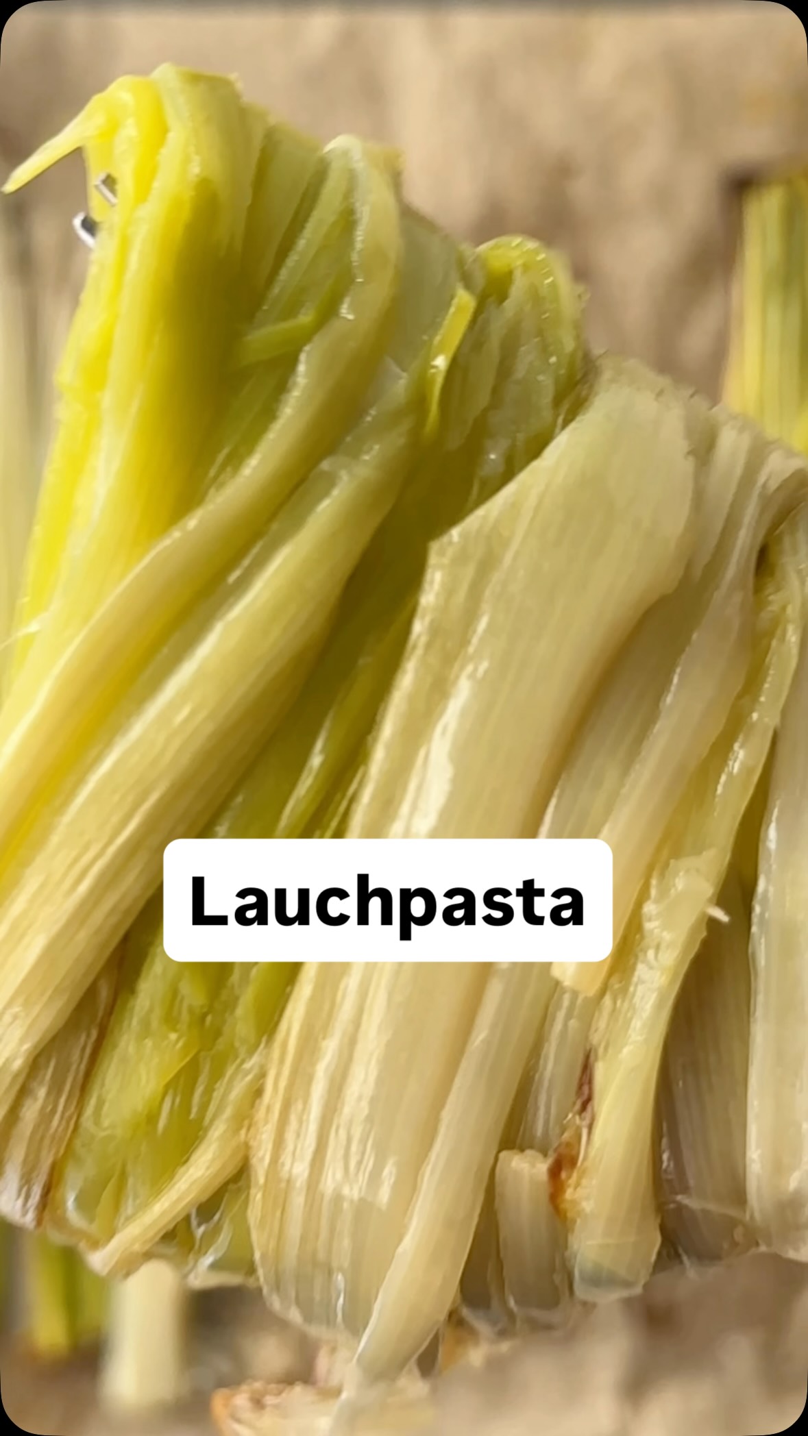 Pasta mit rauchigem Ofen-Lauch auf einem weißen Teller, garniert mit gerösteten Pinienkernen und frischem Thymian, serviert auf einem rustikalen Holztisch.